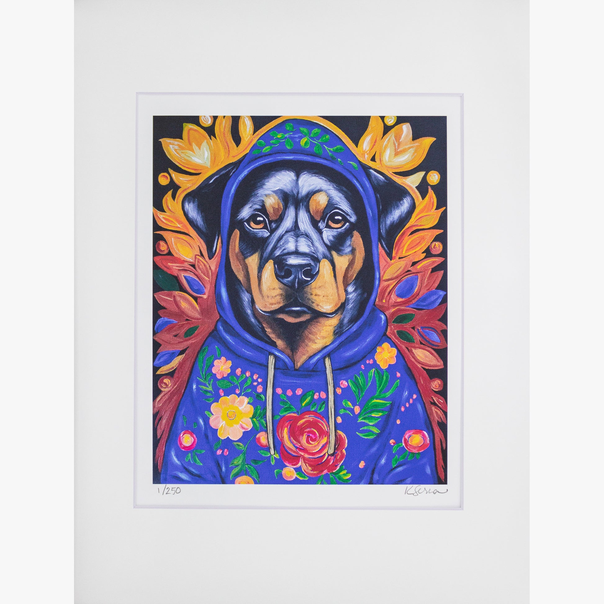 A close-up of a limited edition print featuring Buster the Rottweiler, a dignified dog wearing a deep blue hoodie adorned with colorful floral embroidery. The background showcases warm golden autumn leaves, creating a vibrant contrast. The print is matted with a white border, and the artist’s signature and edition number (1/250) are visible at the bottom.