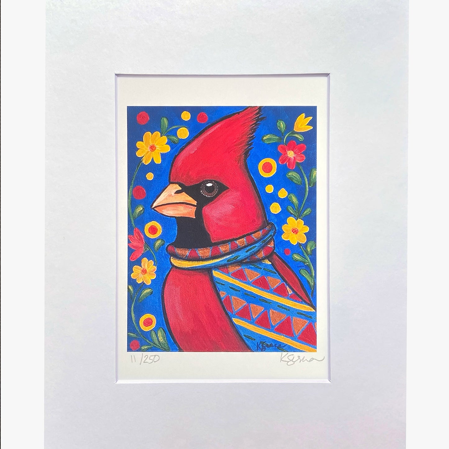 Framed artwork of a red cardinal bird with floral patterns on a blue background.