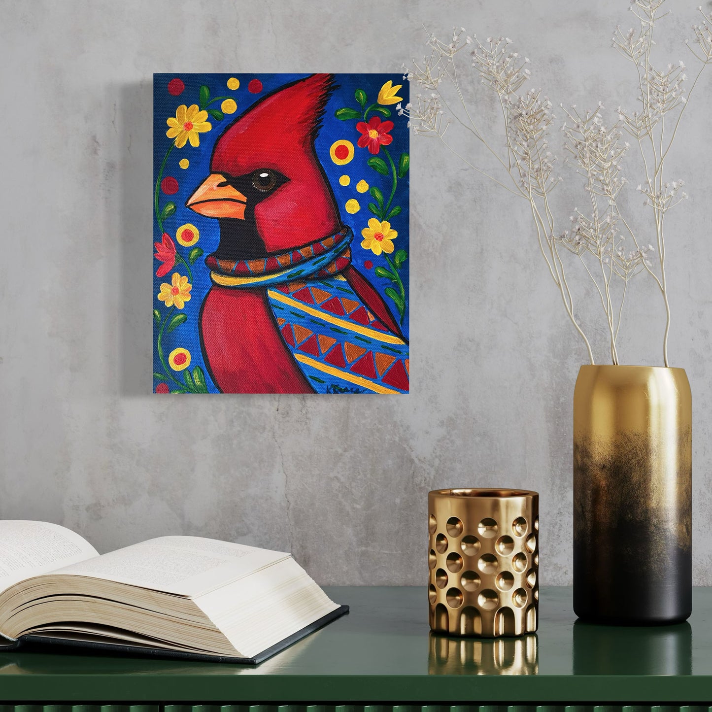 Painting of a red cardinal bird with flowers on a wall above a table with books and decorative items.