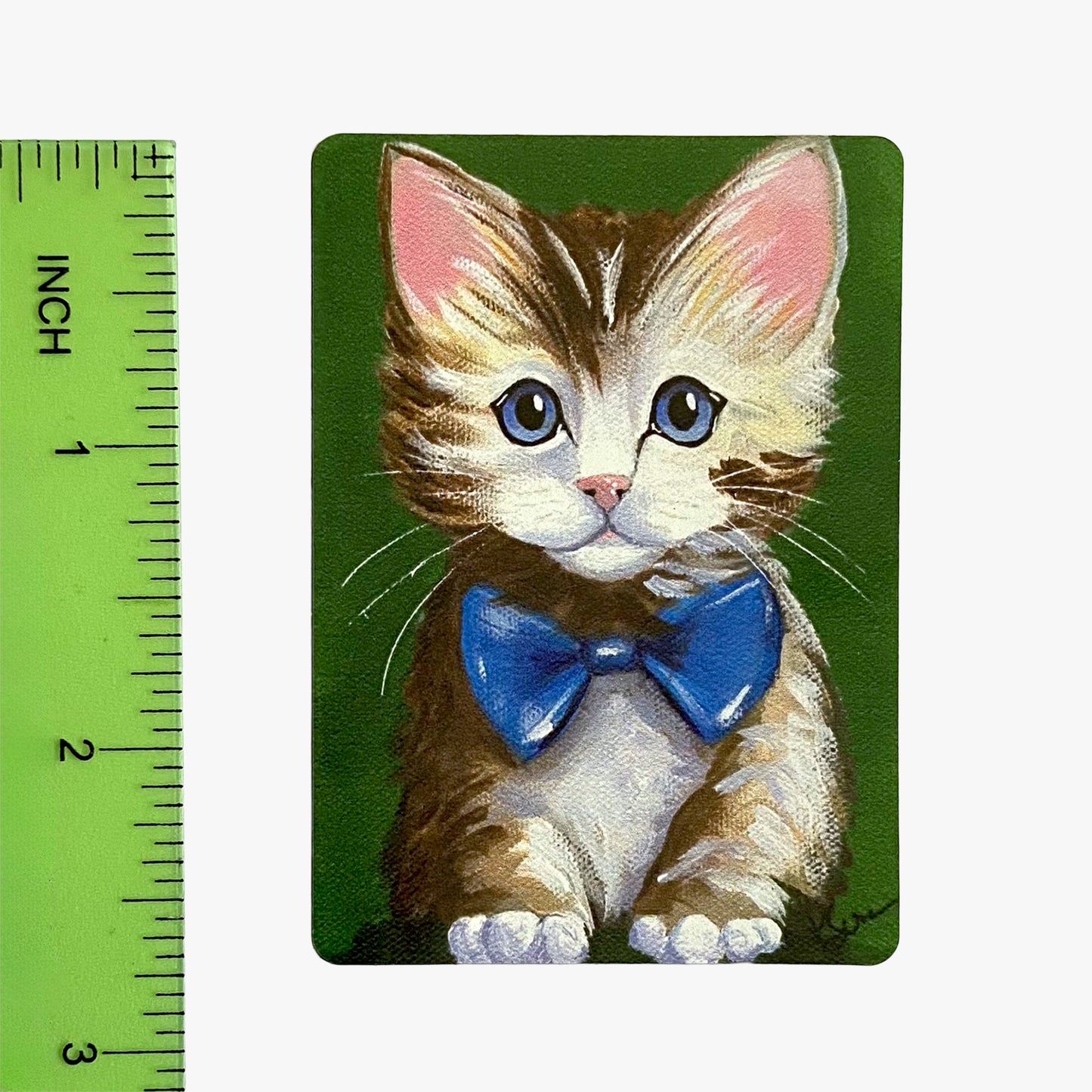 Illustration of a kitten with a blue bow tie on a green background with a ruler for scale.