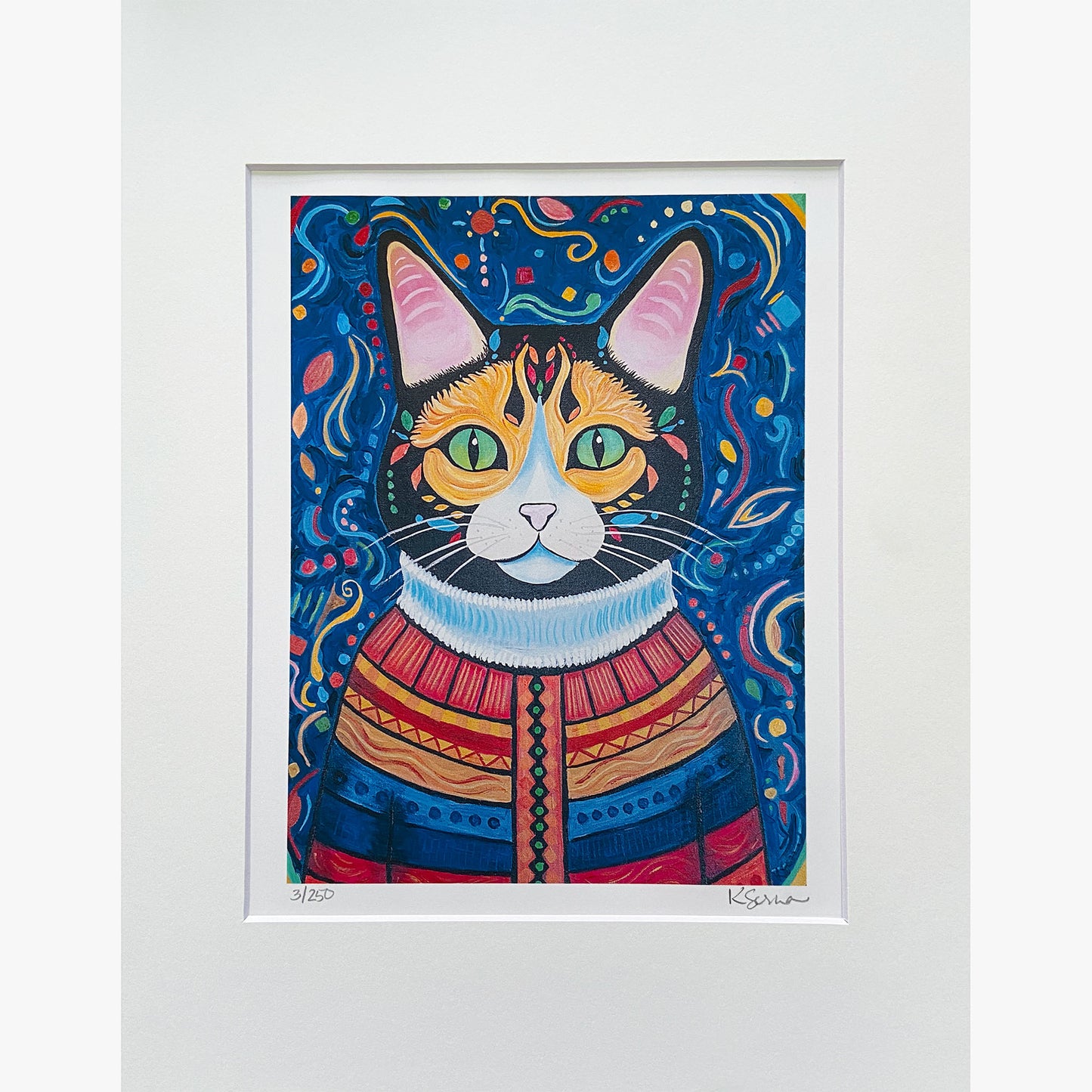 A close-up of a limited edition print featuring Hazel the Cat, a striking calico with green eyes and intricate facial markings. Hazel wears a richly patterned sweater with bold red, blue, and gold hues, detailed with geometric designs and a high white collar. The deep blue background is swirling with vibrant abstract shapes. The print is matted with a white border, and the artist's signature and edition number (3/250) are visible at the bottom.