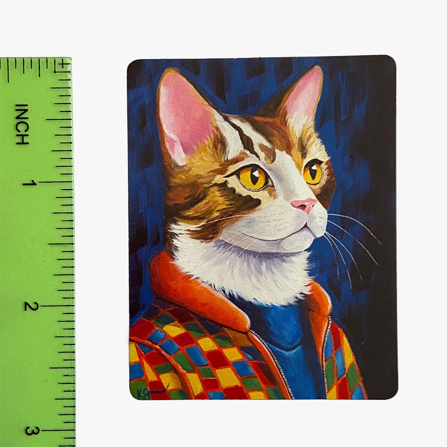 Painting of a cat wearing a colorful jacket next to a ruler for scale.