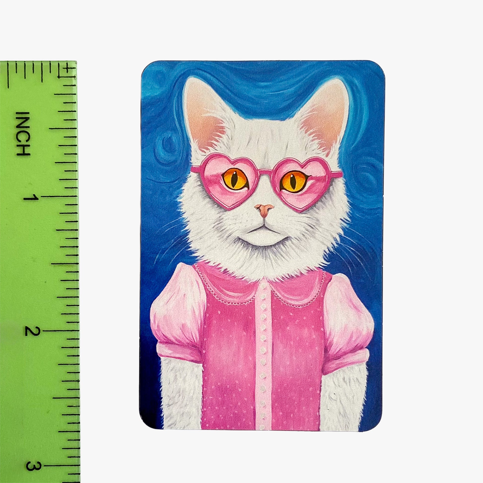 Magnet with a cat wearing pink heart-shaped sunglasses and a pink outfit, next to a ruler for scale.