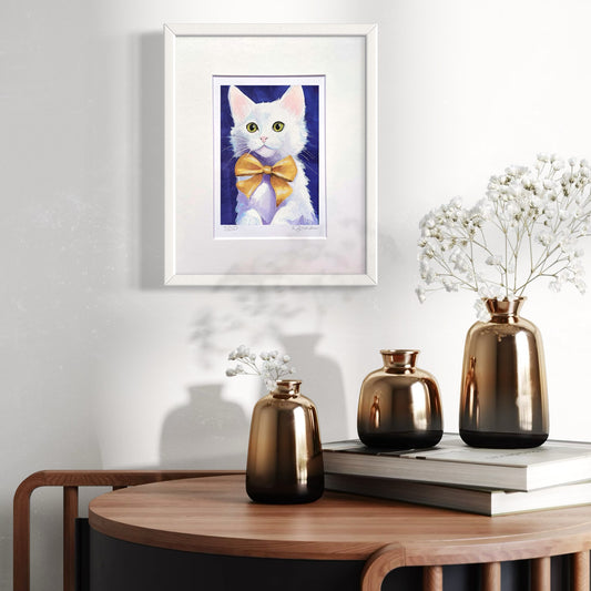 Framed artwork of a cat with a yellow bow tie on a wall above a wooden table with decorative vases.