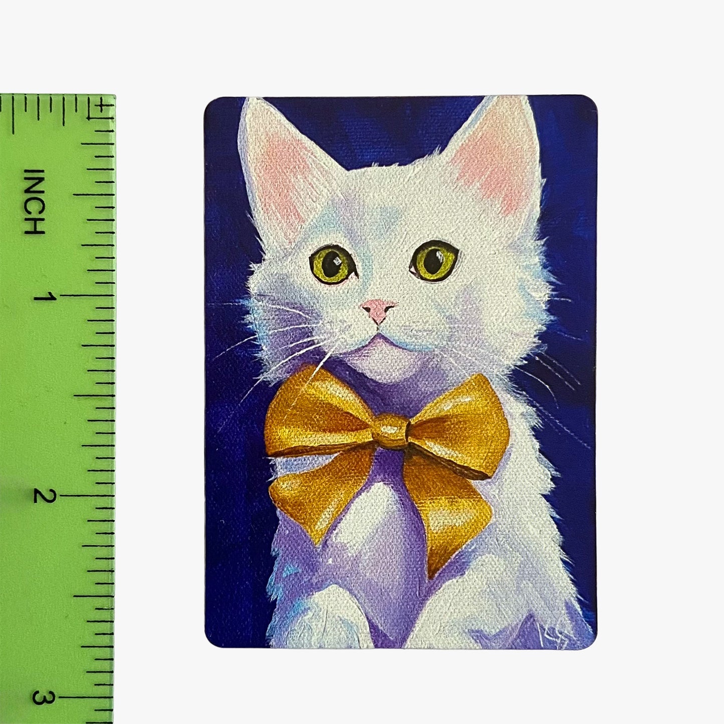 Painting of a white cat with a gold bow tie next to a ruler for scale.