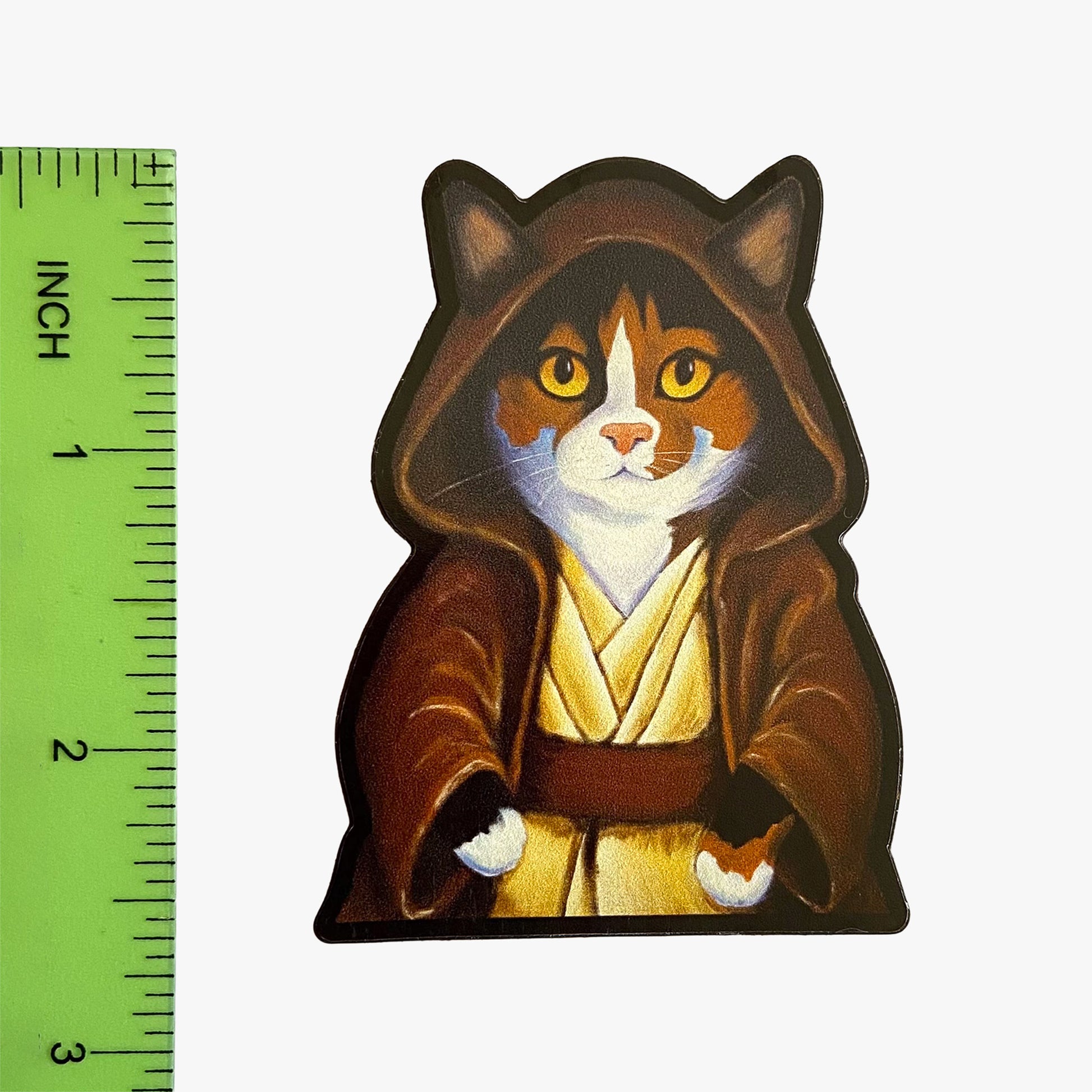 Cat-shaped figure in a Jedi robe next to a ruler on a white background