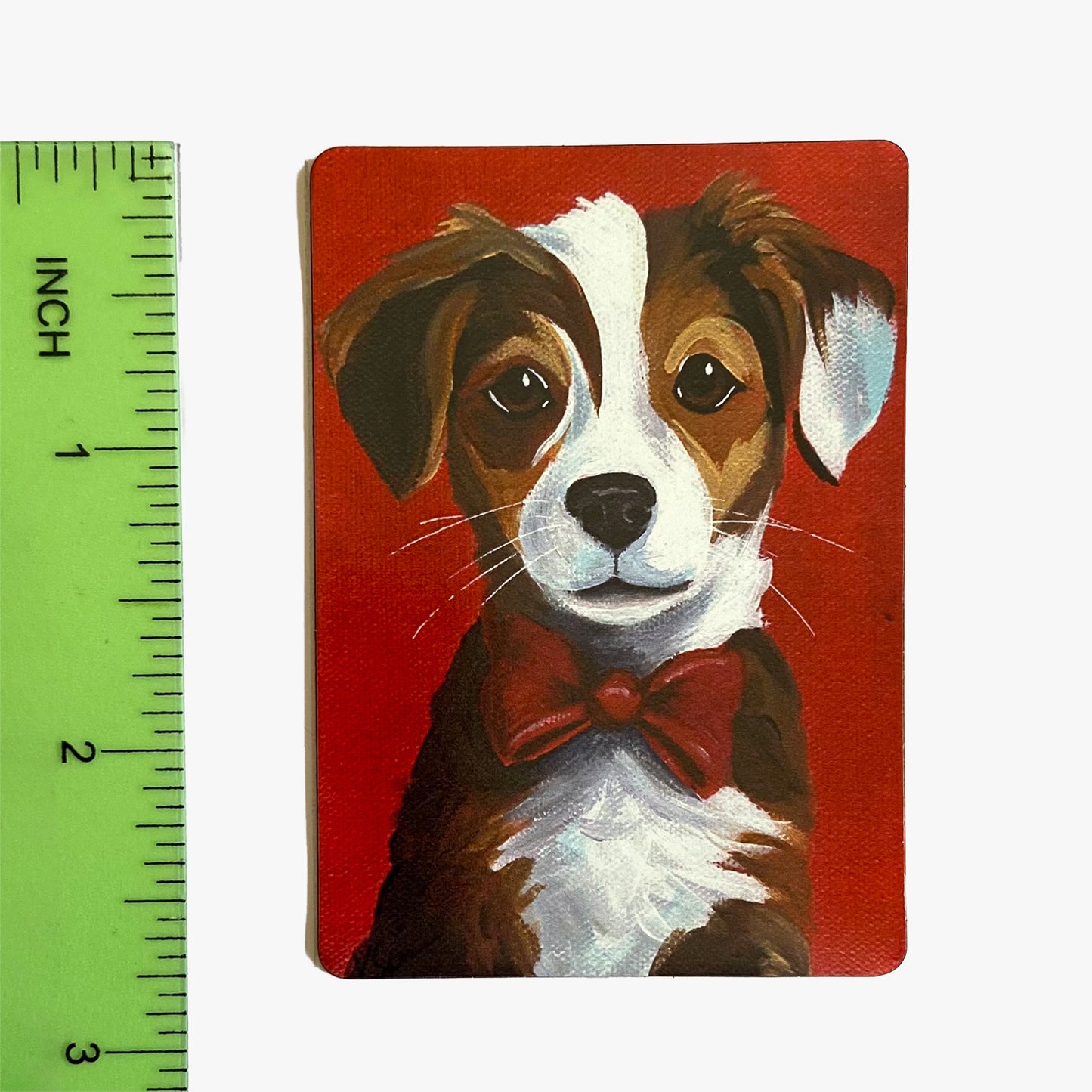 Painting of a dog with a red bow tie on a red background, next to a ruler for scale.