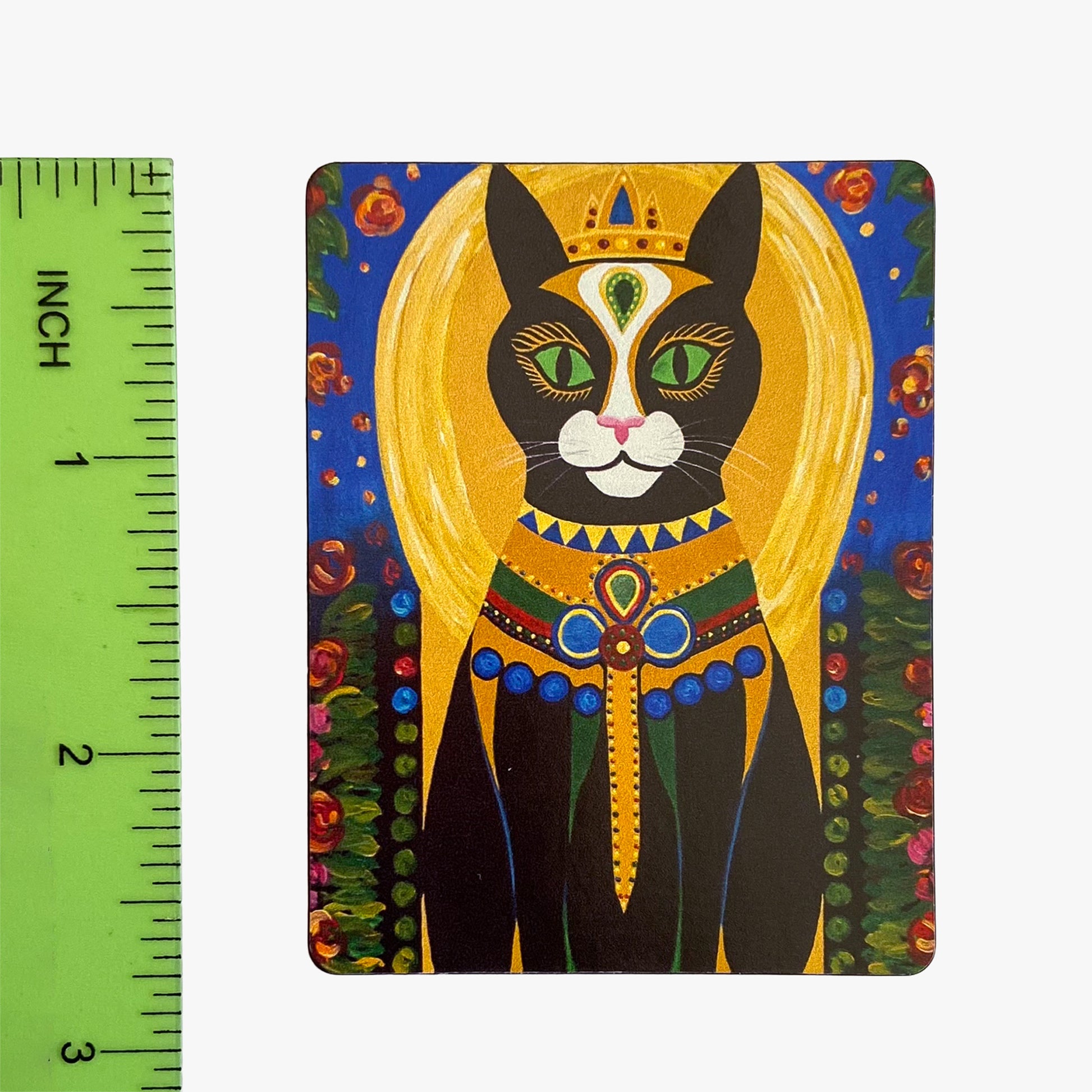 Decorative magnet with a stylized cat design next to a ruler for scale.