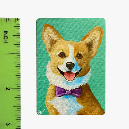 Magnet with a corgi dog wearing a purple bow tie on a teal background, next to a ruler for scale.