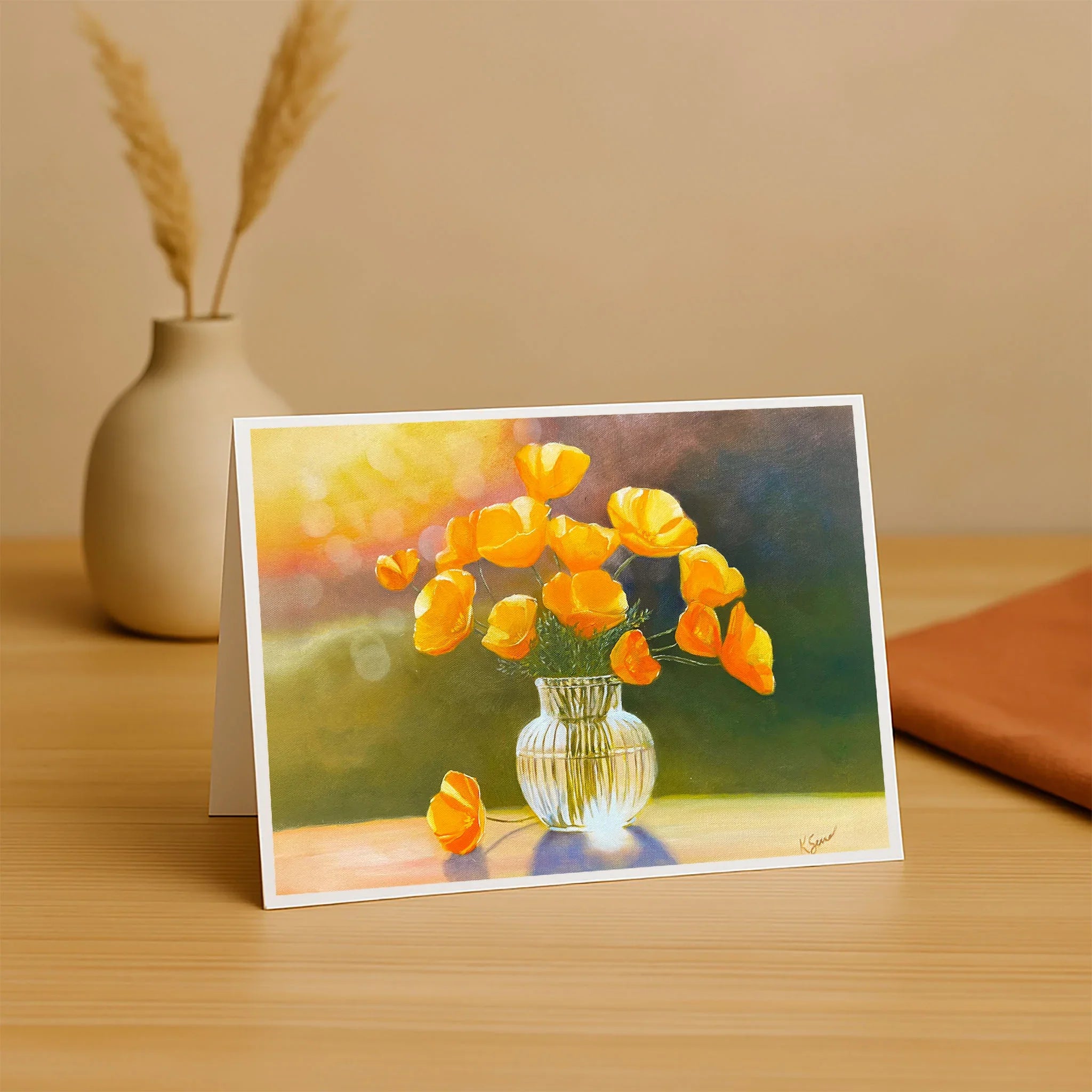Greeting card with a painting of yellow tulips in a clear vase on a wooden surface.