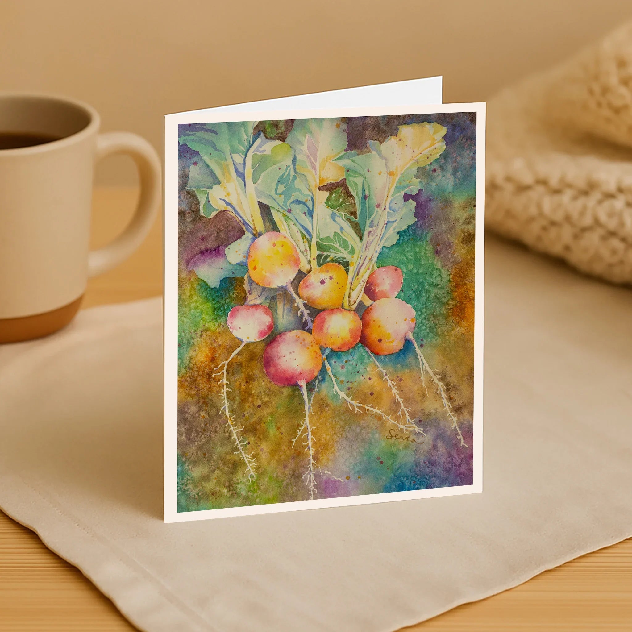 Colorful greeting card with nature-themed design on a table with a mug and fabric.