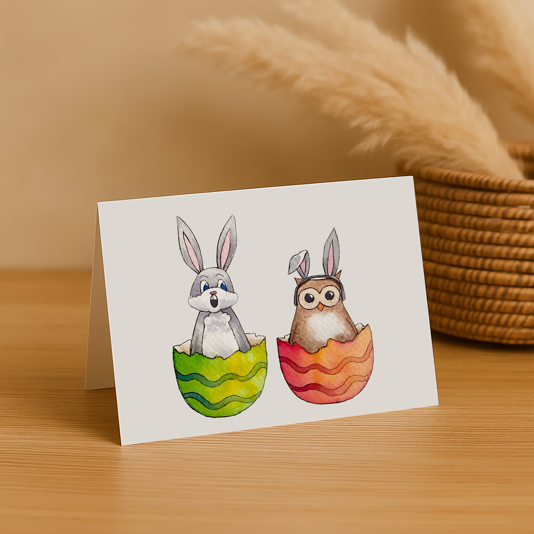 Greeting card with cartoon rabbit and owl in Easter eggs on a wooden surface.
