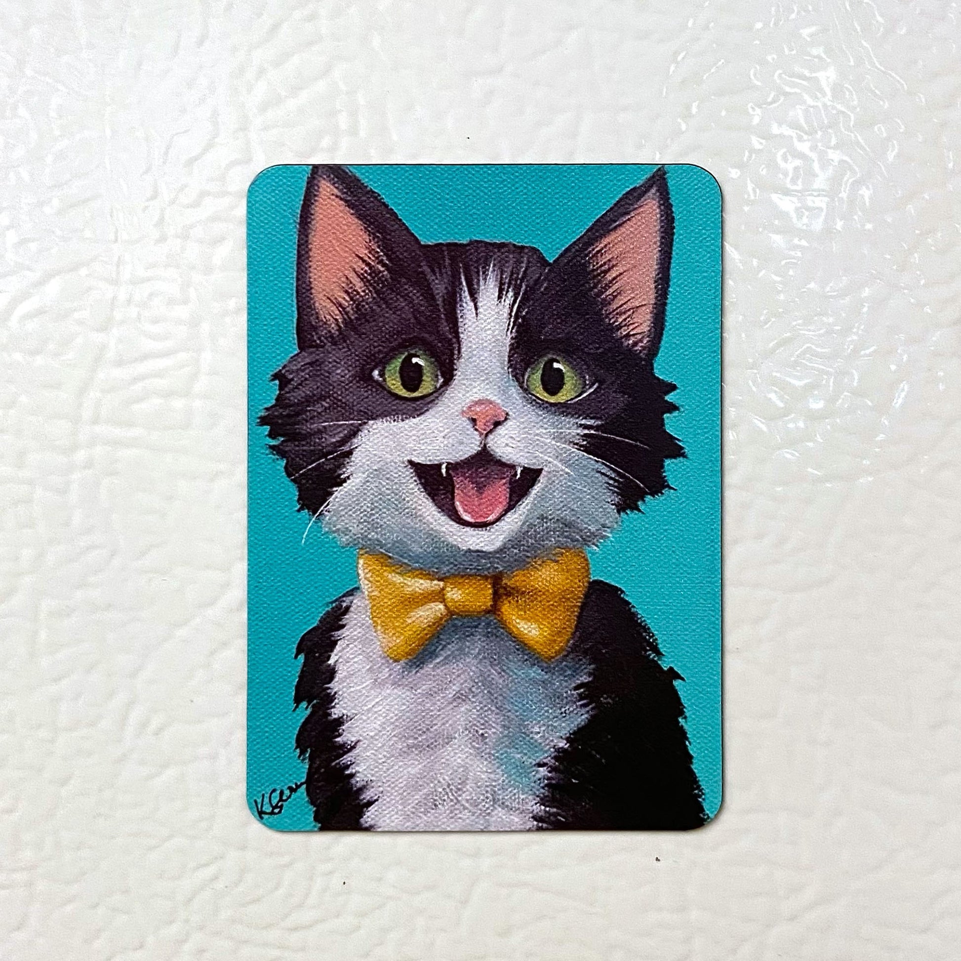 Fridge magnet with a cartoon cat wearing a yellow bow tie on a white background
