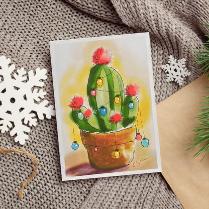 A watercolor and ink painting of a green cactus in a clay pot decorated with colorful Christmas lights and red pom-pom blossoms.