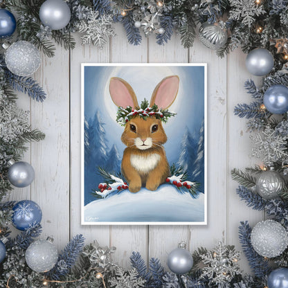 artwork of a rabbit with a wreath surrounded by Christmas decorations on a wooden surface.