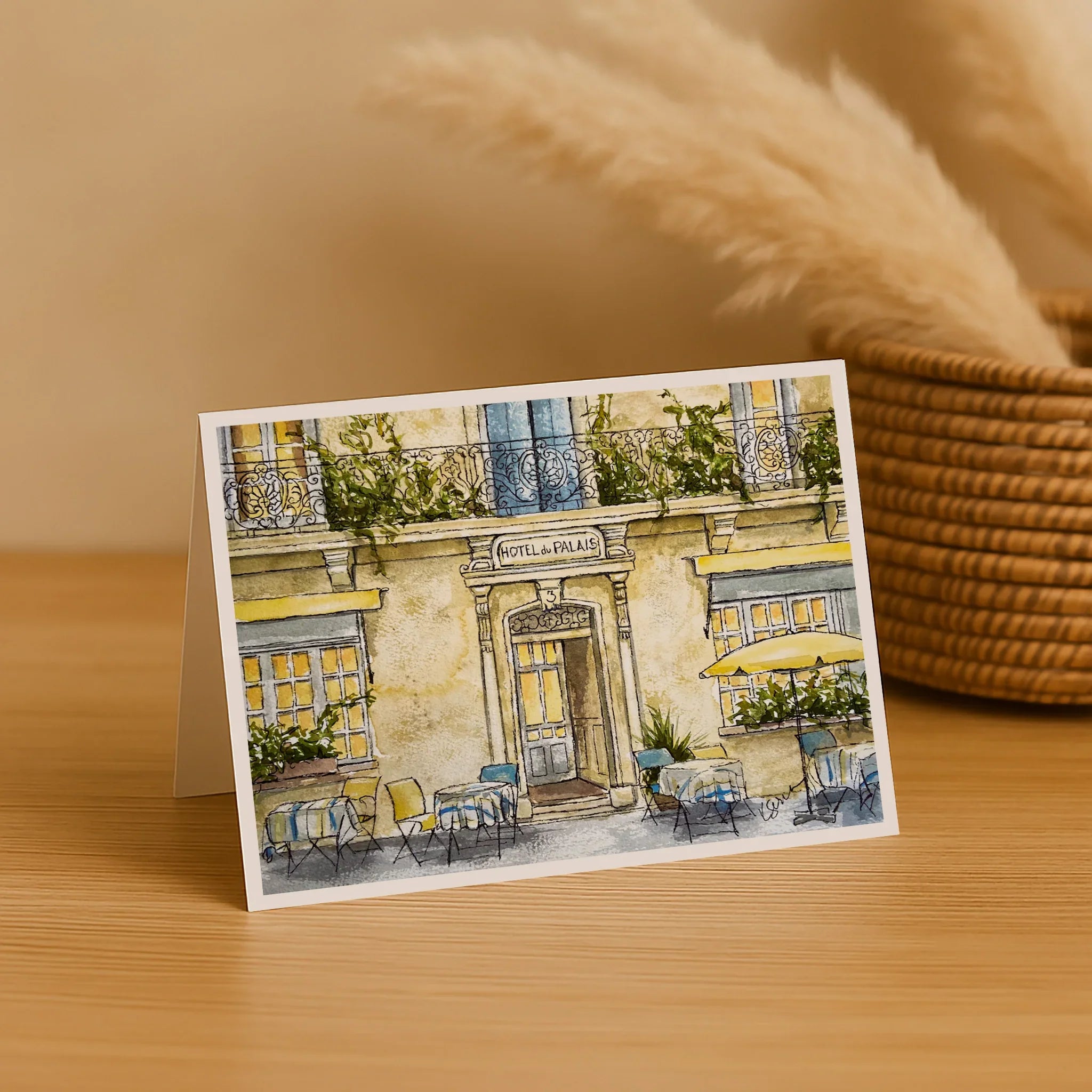 Greeting card with a painting of a café on a wooden surface with decorative elements.
