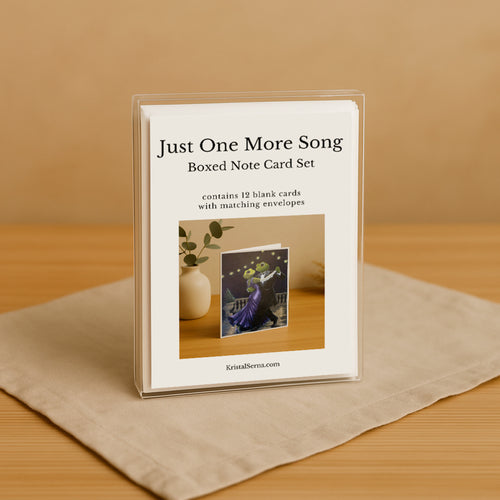Boxed note card set titled 'Just One More Song' on a beige surface with a brown background
