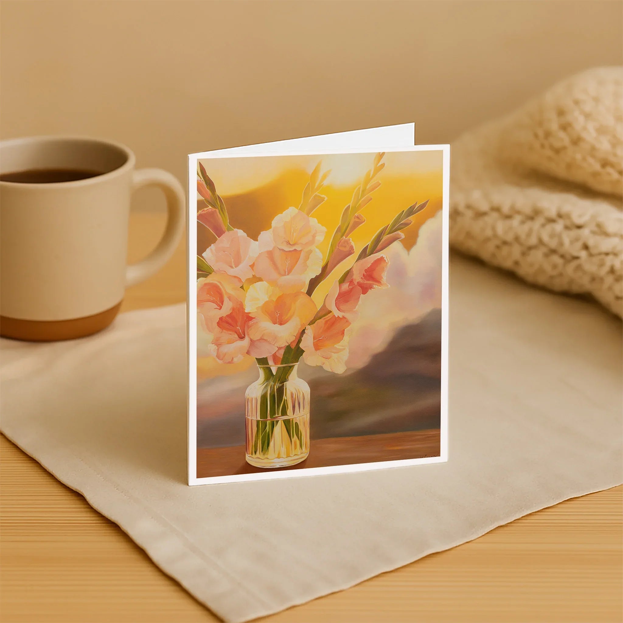 Greeting card with floral design on a table with a mug and blanket.