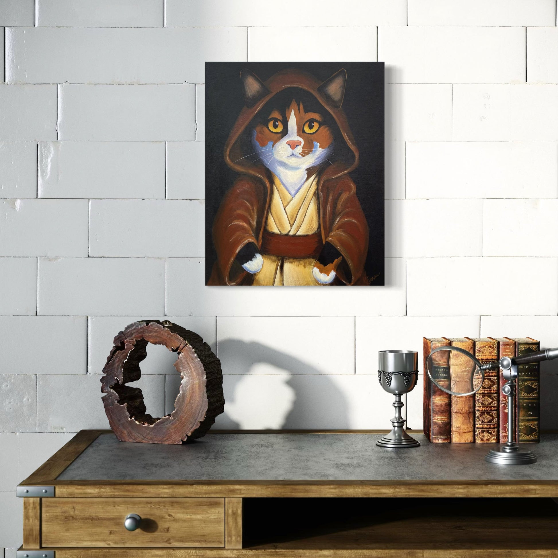 Cat painting in a hooded robe on a wall above a wooden shelf with decorative items.