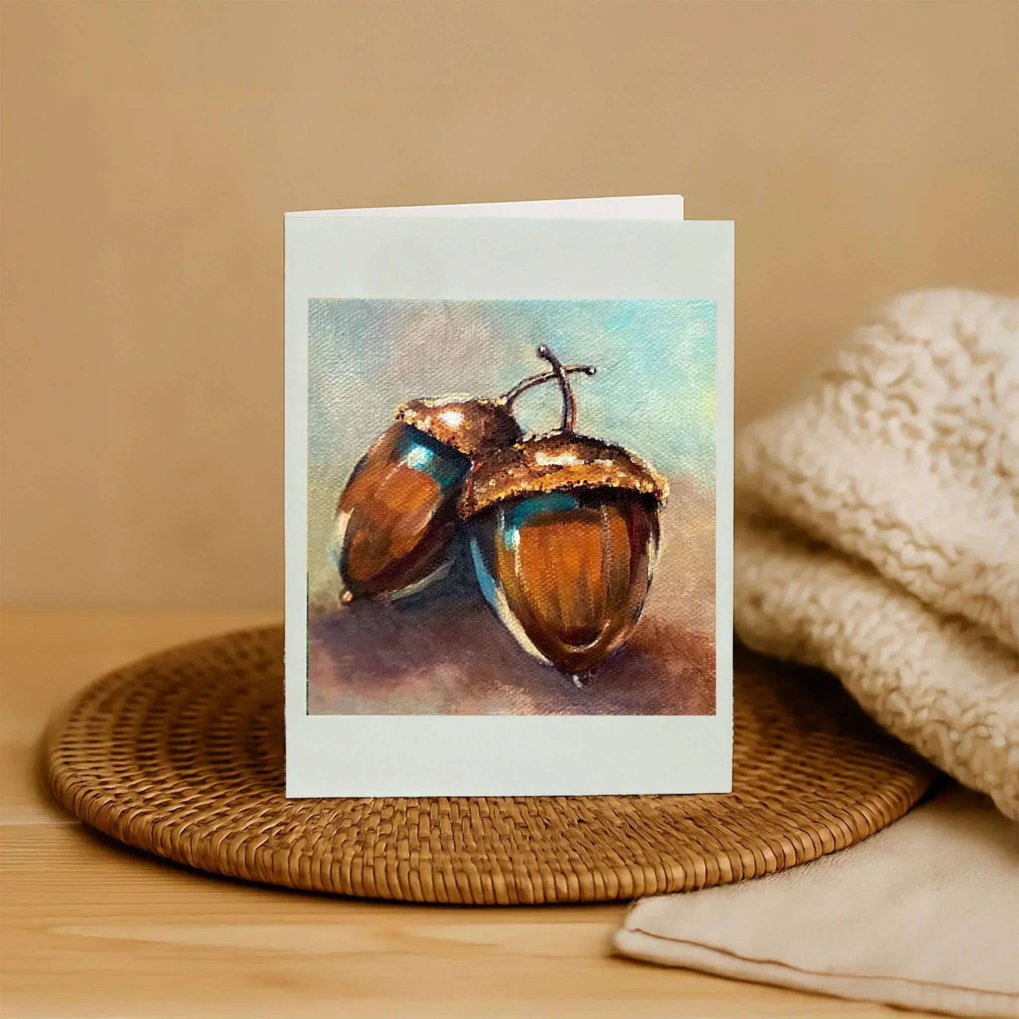 Greeting card with acorn design on a woven mat and beige fabric background