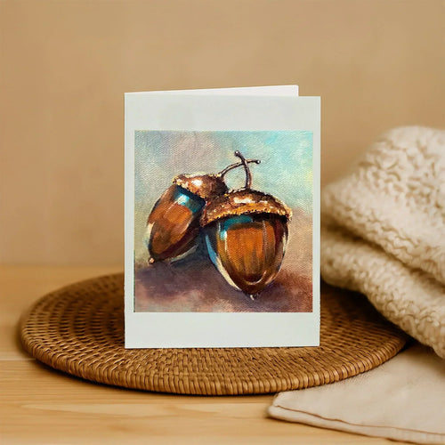 Greeting card with acorn design on a woven mat and beige fabric background