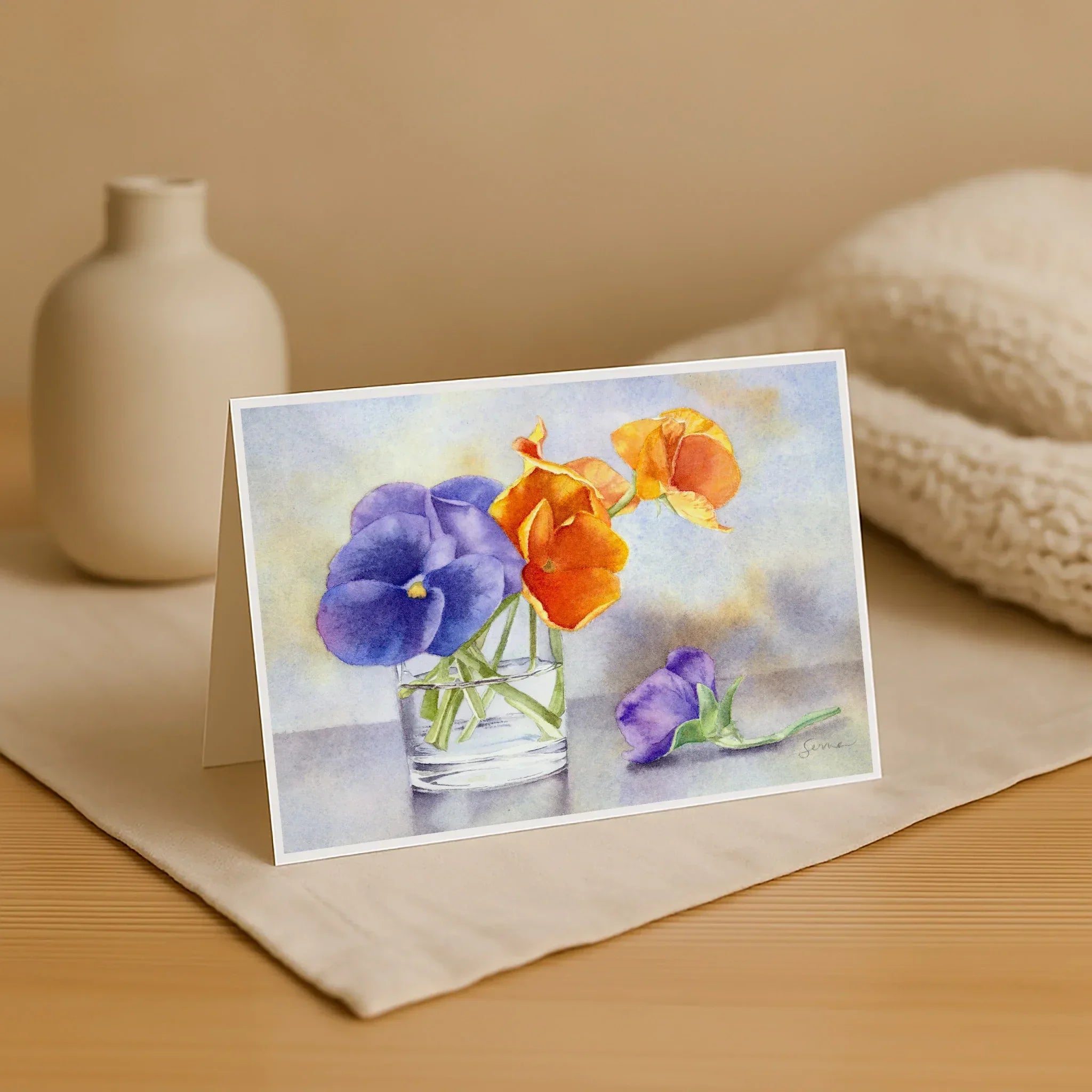 Greeting card with a watercolor design of flowers on a wooden surface.