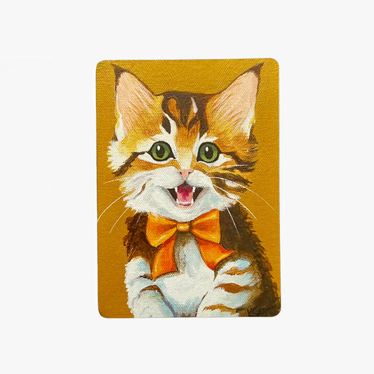 Magnet with a cartoon cat wearing a bow tie on a mustard yellow background