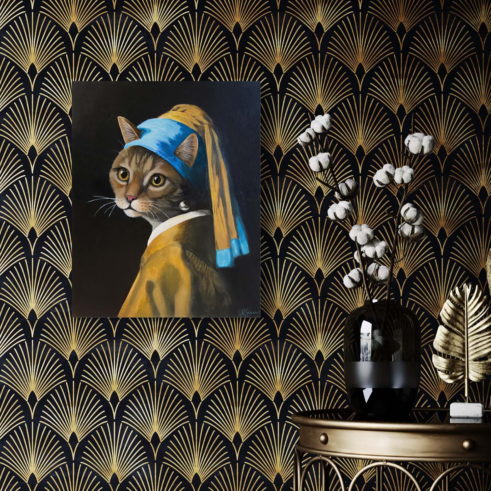 Cat wearing a blue headscarf with a pearl earring on a decorative wall with gold and black pattern.