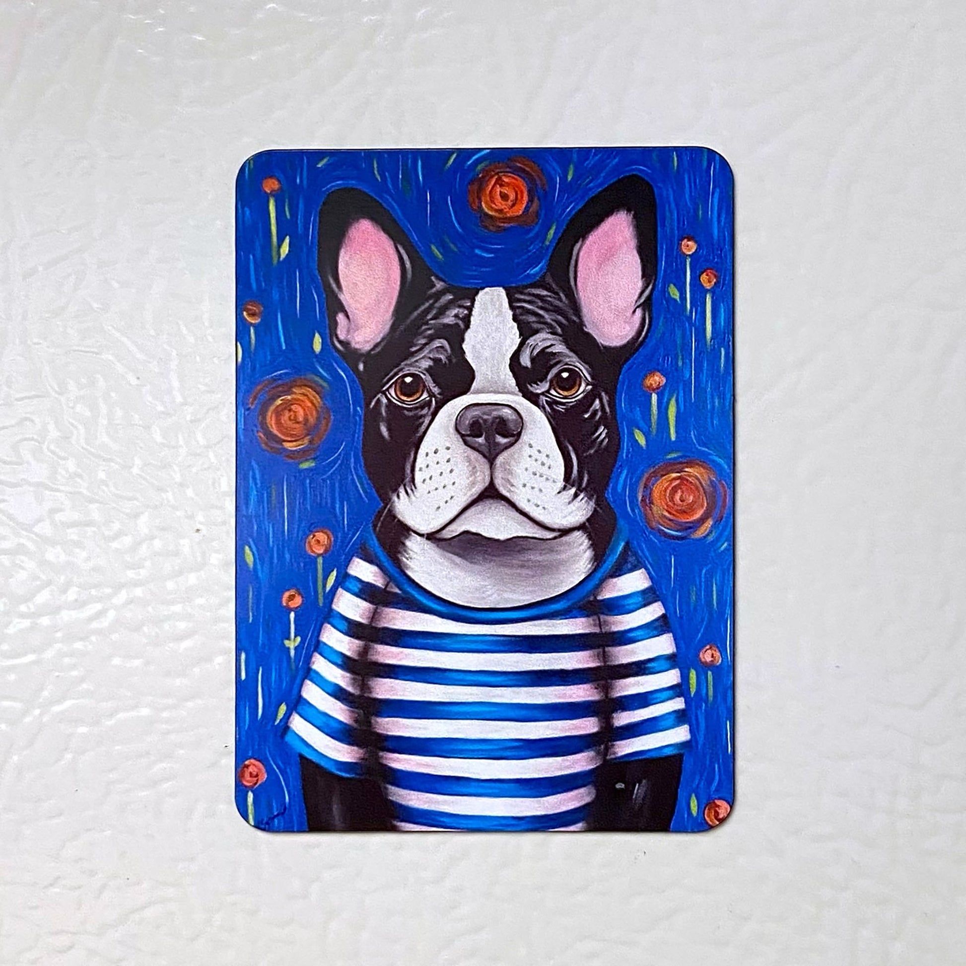 Fridge magnet with a dog illustration wearing a striped shirt on a white background