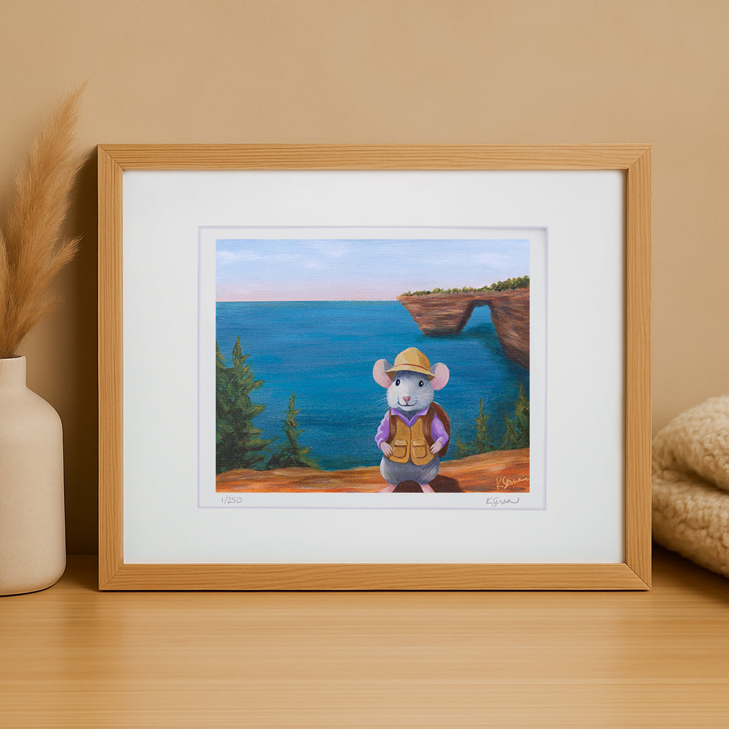 Framed illustration of a mouse in a hat and backpack standing on a cliff overlooking the ocean.