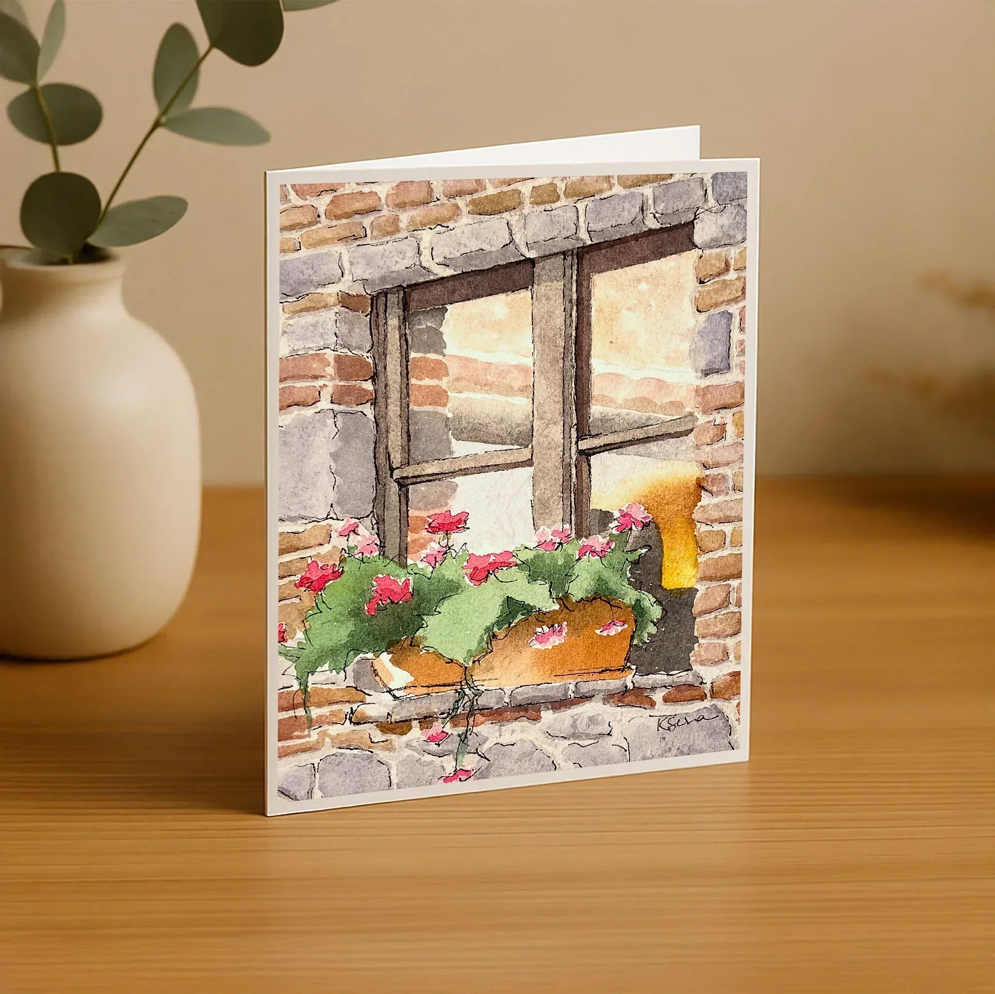 Greeting card with a brick wall and window design on a wooden surface.