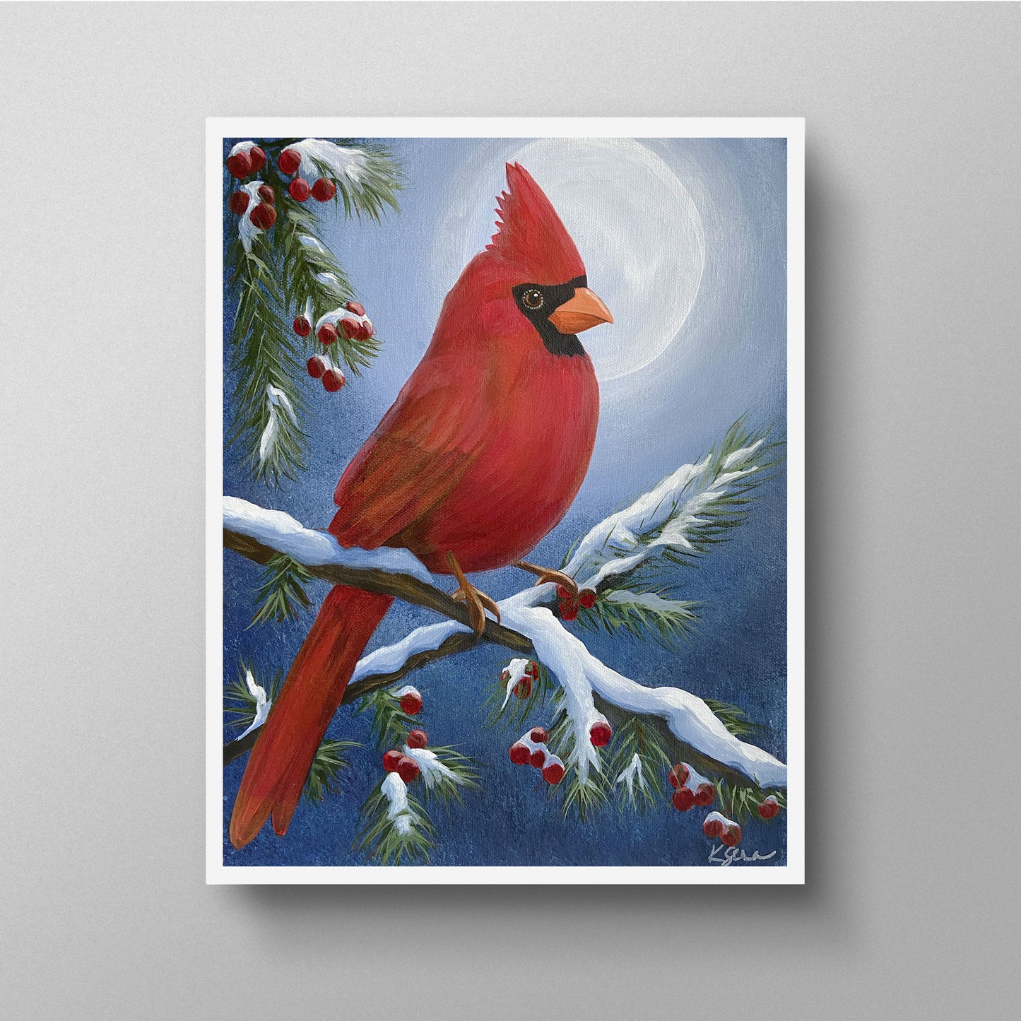 Framed artwork of a red cardinal bird on a branch with snow and berries against a blue sky.