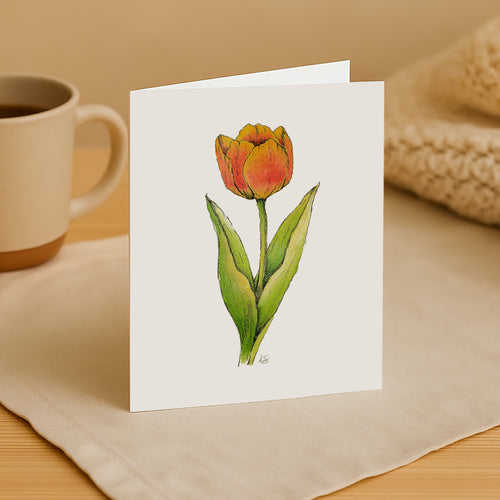 Greeting card with a tulip illustration on a beige surface with a mug and woven item.