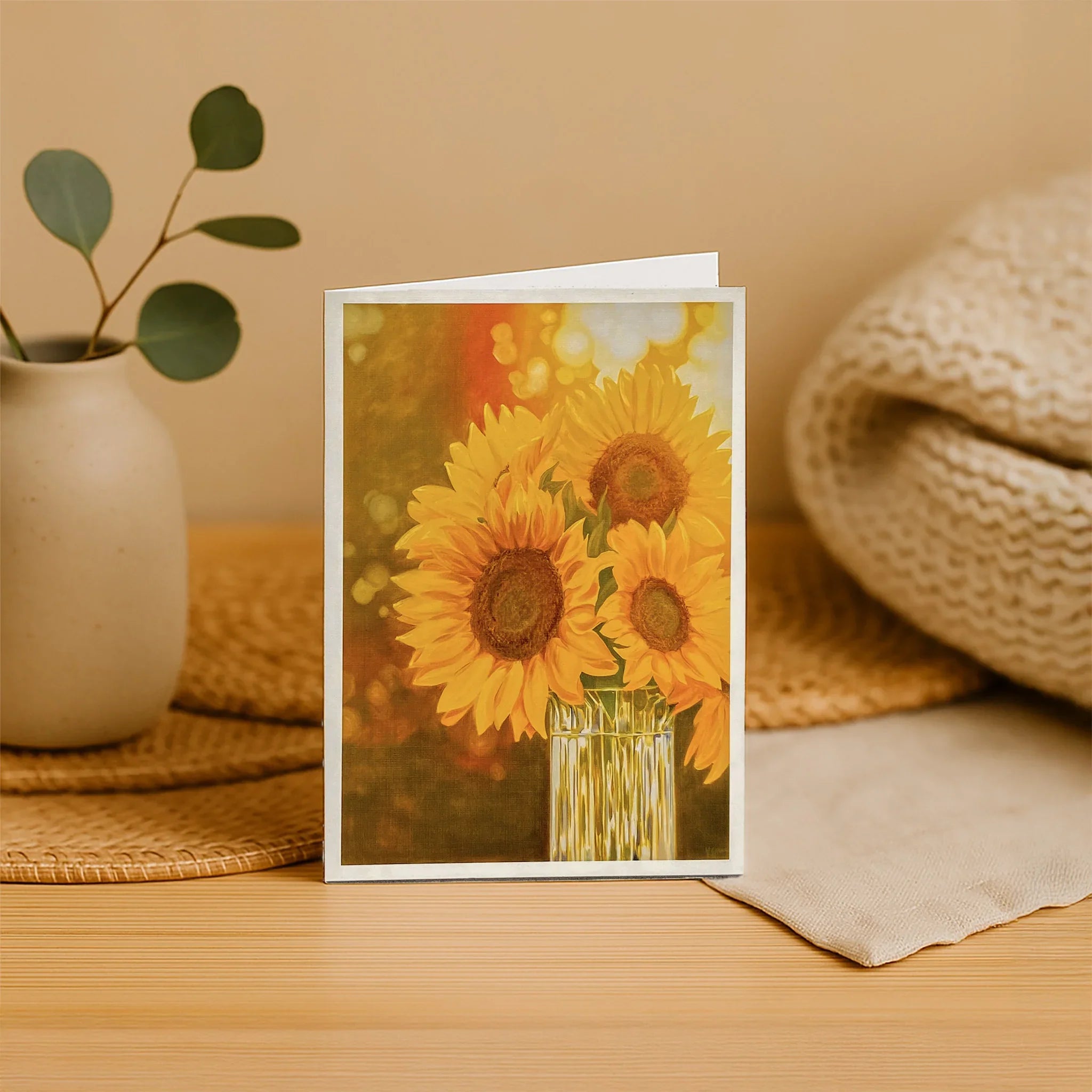 Greeting card with sunflower design on a wooden surface with decorative items.