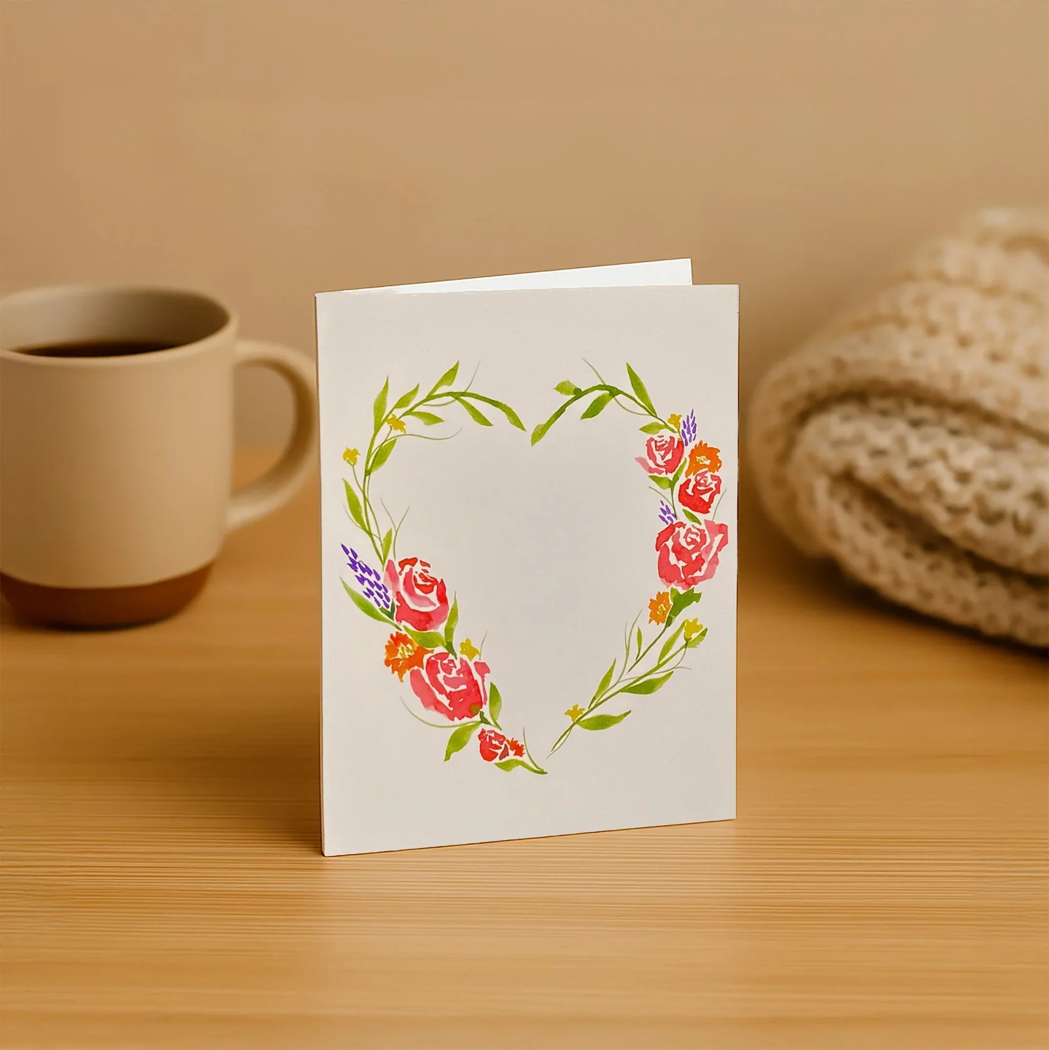 Floral card on a wooden surface with a cup of coffee and knitted item in the background