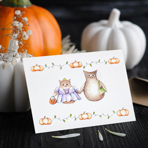 A Halloween greeting card depicting an illustration of two owls, one adult and one child, dressed in costumes and trick-or-treating, with a background of pumpkins and leaves.