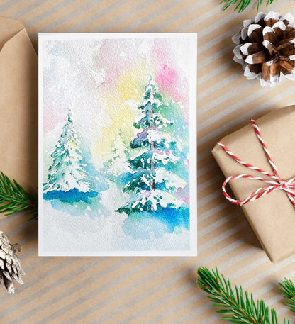 A watercolor painting of snow-covered evergreen trees with soft pink, yellow, and blue tones suggesting a misty sunrise in winter.